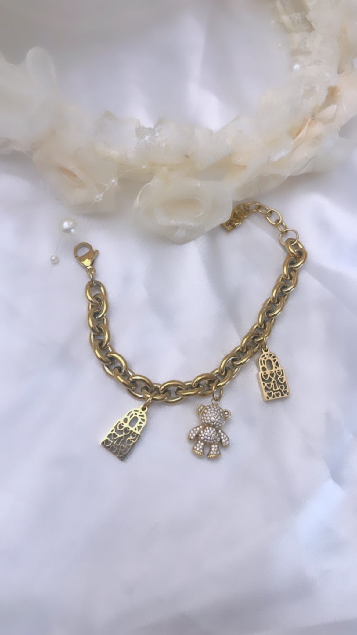 Bracelet chaîne doré au design élégant et moderne, agrémenté de charms raffinés : deux pendentifs ajourés aux motifs de cœurs et un adorable ourson serti de strass scintillants.