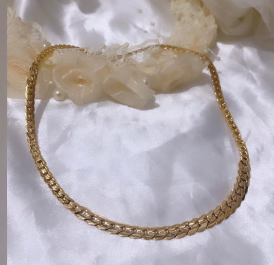 Collier au design moderne et élégant, caractérisé par des maillons entrelacés et brillants qui captent la lumière avec raffinement.